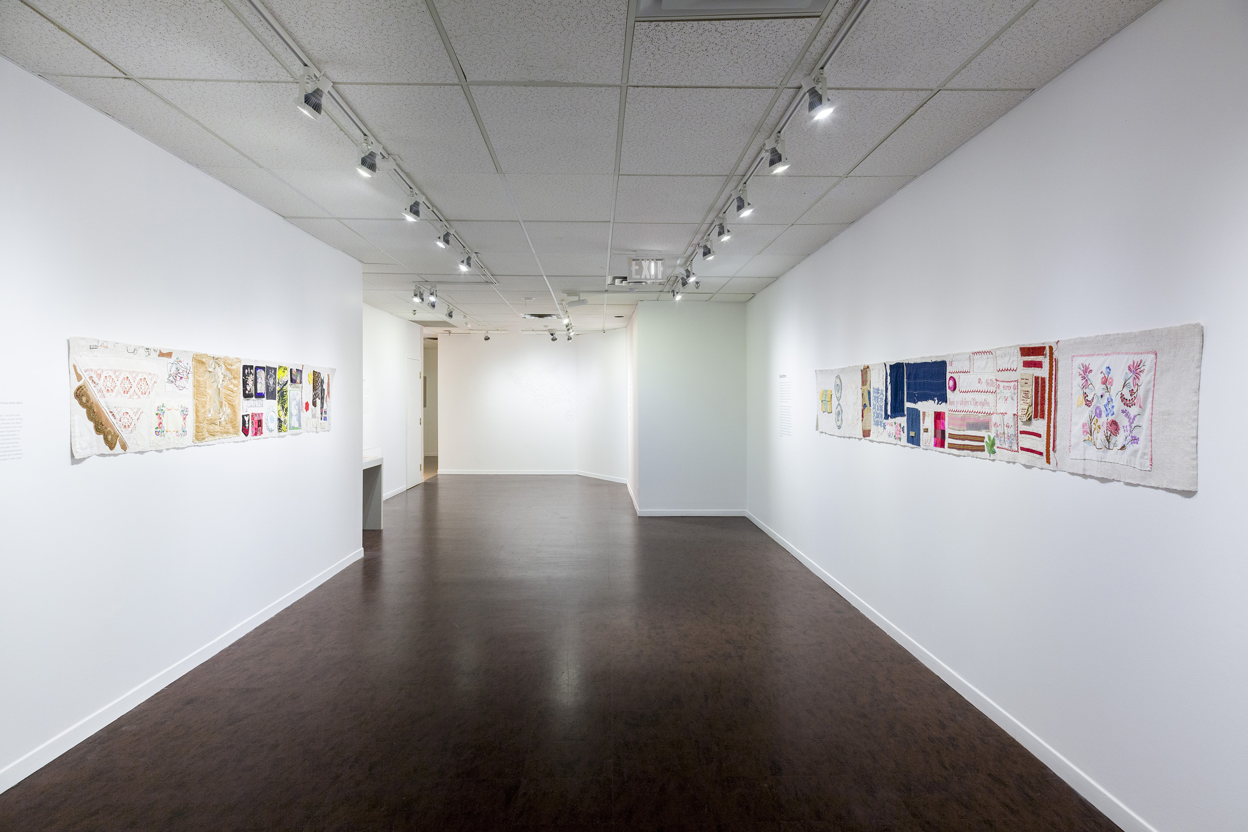 A long gallery with two long narrow hangings with patches of different fabric sewn on