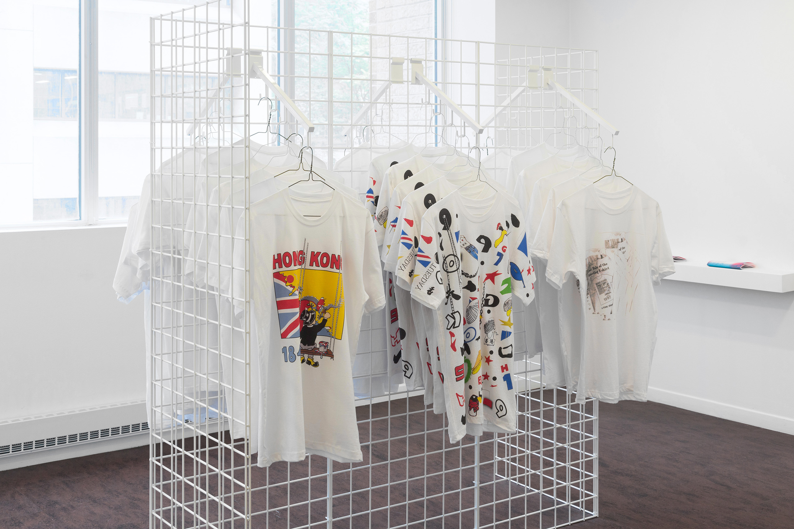 Three t-shirts hanging on a white wire frame