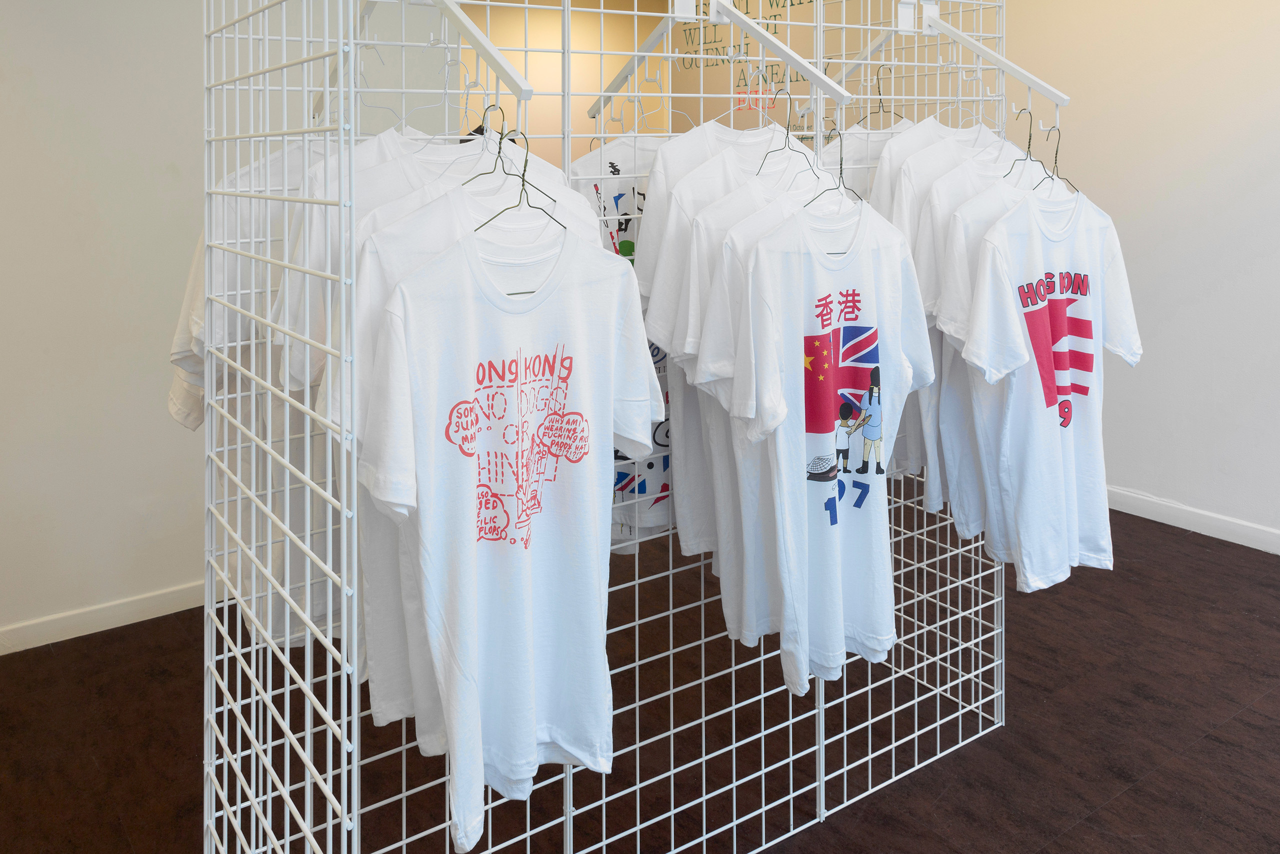 Close up of three sets of t-shirts hanging on a white wire rack.