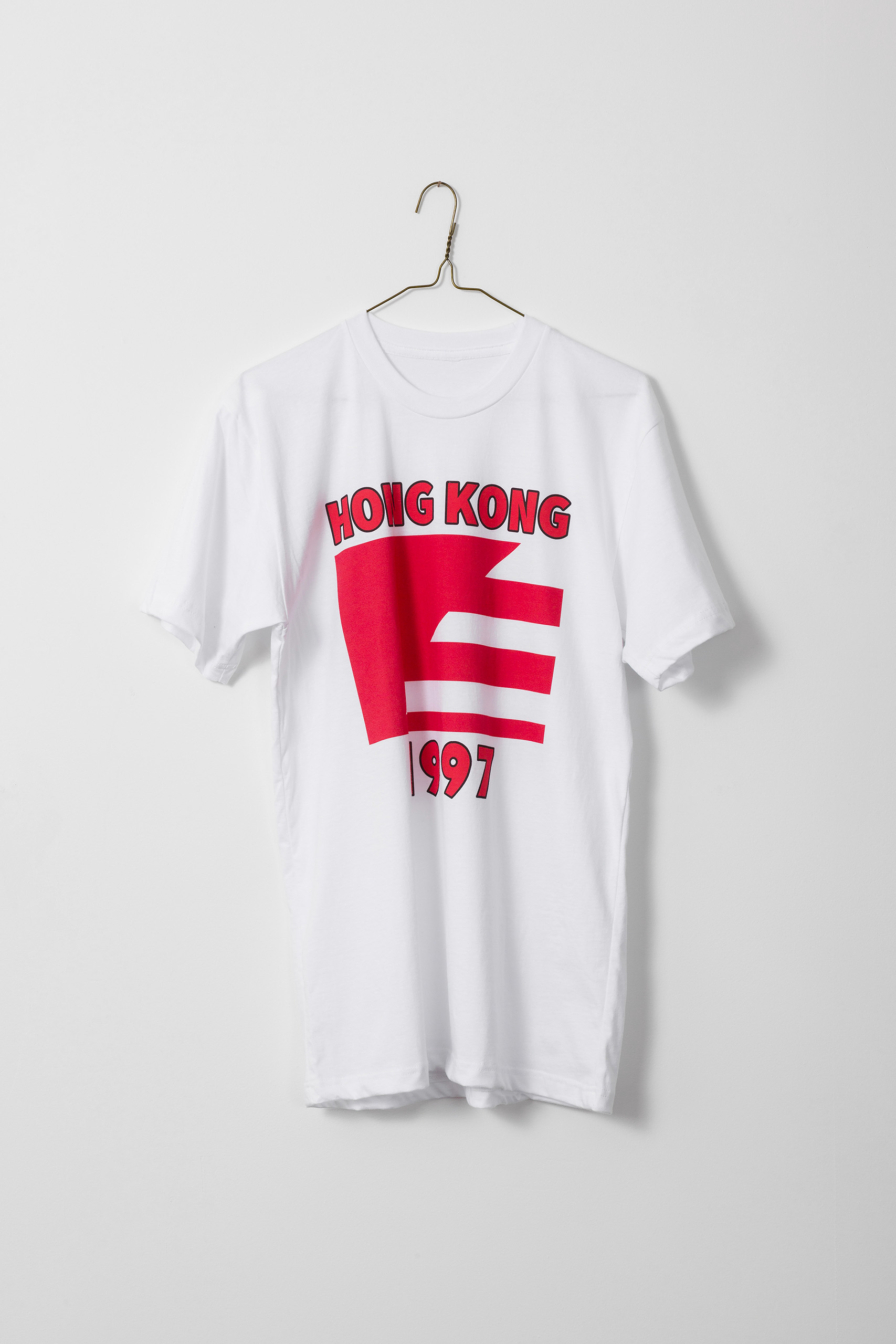 White t-shirt with "Hong Kong" above a flag divided on an angle, half red and half red and white stripes. "1997"