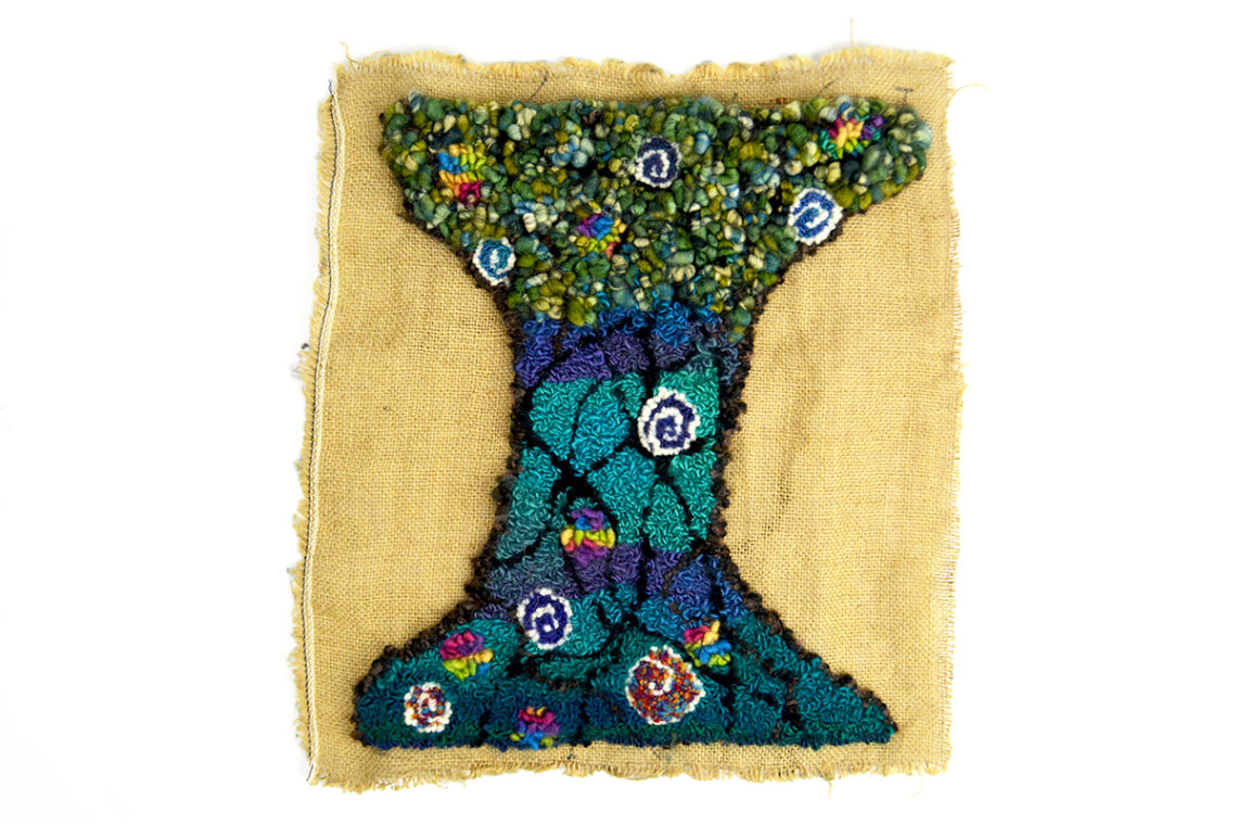 The image shows a textile artwork, shaped like an I , in green and blue yarn and wool